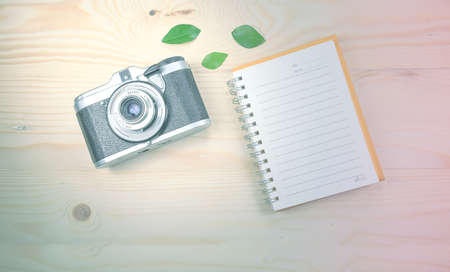 Vintage camera on wooden background with notebook. Vintage toneの写真素材