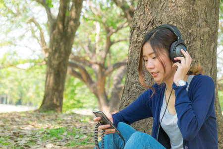 Young girl listening to music in city park.の写真素材