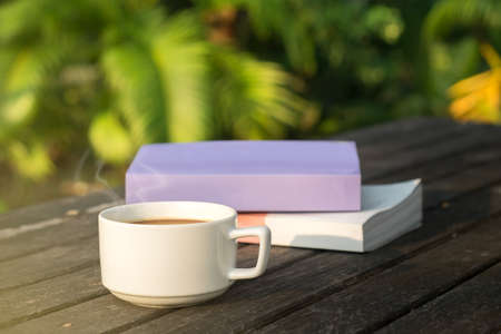 Cup of coffee and a book on a wooden table.の写真素材