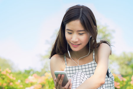 Beautiful young woman listening music in the park.