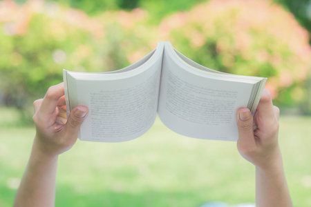 Woman hand's holding book in the park.