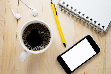 Coffee cup with notebook on wooden table.の写真素材