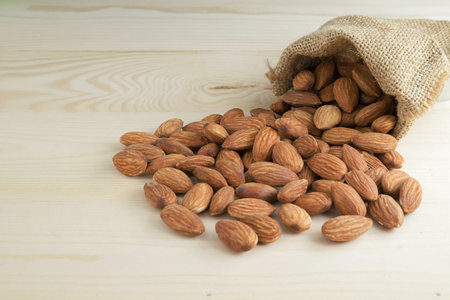 Almonds in sack bag on wooden table.の写真素材
