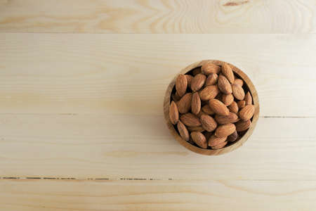 Almonds in a bowl on wooden table.の写真素材