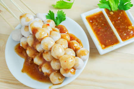 Meatball in white plate with thai spicy sauce on wooden table.の写真素材