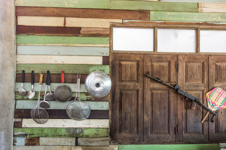 a lot of cooking instruments hang on the wooden wall near the windows and the old gunの写真素材