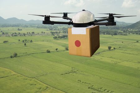 drone flying transportation in agriculture concept, smart farmer use a drone(artificial intelligence technology delivery to send a tool kit, product, fruit, vegetable in the farm,  to another placeの写真素材