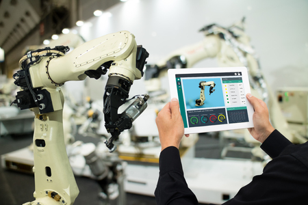 iot industry 4.0 concept,industrial engineer using software (augmented, virtual reality) in tablet to monitoring machine in real time.Smart factory use Automation robot arm in automotive manufacturingの写真素材