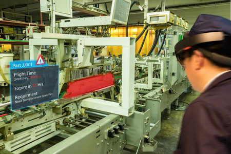 iot smart industry 4.0 concept. Industrial engineer(blurred) using smart glasses with augmented mixed virtual reality technology to see the detail of part which will expired and prepare spare partsの写真素材