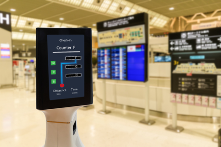 Smart robotic technology concept, The passenger follow a service robot to a counter check in in airport, the robot can help and give some information to passenger quicklyの写真素材