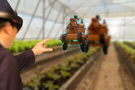 iot smart industry robot 4.0 agriculture concept,agronomist,farmer(blurred) using smart glasses (augmented mixed virtual reality,artificial intelligence technology) to monitoring  autonomous roboticsの写真素材