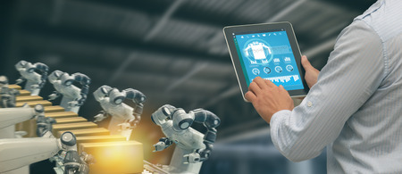 iot industry 4.0 concept,industrial engineer using software (augmented, virtual reality) in tablet to monitoring machine in real time.Smart factory use Automation robot arm in automotive manufacturingの写真素材