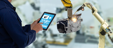 iot industry 4.0 concept,industrial engineer using software (augmented, virtual reality) in tablet to monitoring machine in real time.Smart factory use Automation robot arm in automotive manufacturingの写真素材