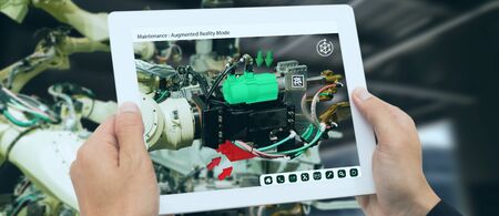 iot industry 4.0 concept,industrial engineer using software (augmented, virtual reality) in tablet to monitoring machine in real time.Smart factory use Automation robot arm in automotive manufacturingの写真素材