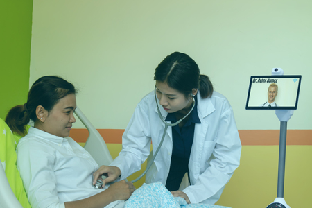 smart technology in medical concept, dotor try to auscultate the patient in room with smart robot with telepresence robot during emergency. (artificial intelligence) technology for better,efficiencyの写真素材