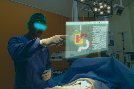 smart medical technology concept, doctor use glasses to use augmented reality to show the injury of stomach of the patient for analysis and find the way to treatment in surgery room at hospitalの写真素材