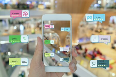 internet of things marketing concepts,smart augmented reality,customer hold the mobile phone to see  the shop type that search by ai application including super market, food zone, bank, cinema etcの写真素材