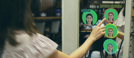 iot smart retail futuristic technology concept, happy girl try to use smart display with virtual or augmented reality in shop or retail to predict select color of new hair by artificial intelligenceの写真素材