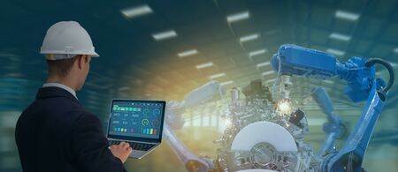 iot industry 4.0 concept,industrial engineer using software (augmented, virtual reality) in tablet to monitoring machine in real time.Smart factory use Automation robot arm in automotive manufacturingの写真素材