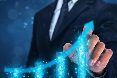 business man point hand on the top of arrow graph with high rate of growth. The success and growing growth graph in the company or industrial after investmentの写真素材
