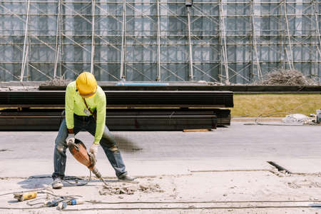 Construction worker  electric drill Drilling concrete ground in construction areaの写真素材