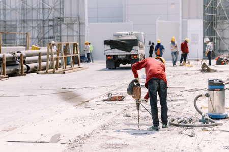 Construction worker  electric drill Drilling concrete ground in construction areaの写真素材