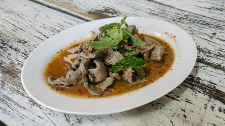 Esan's food,  Scalding Liver pork with spicy garnish in dish on the wooden table,  It's one of most popular foods in Thailand.の写真素材