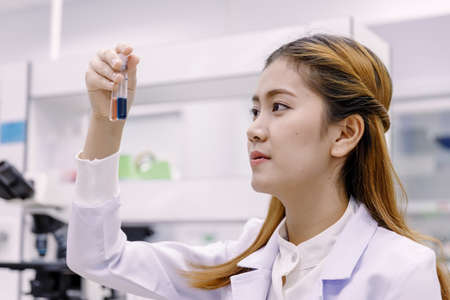 Young Asian researcher looking at the flask in the science laboratory.の写真素材