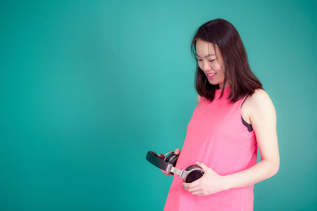 A beautiful Asian woman is pregnant. Wearing a pink shirt Take a big headset Come to the stomach Let...