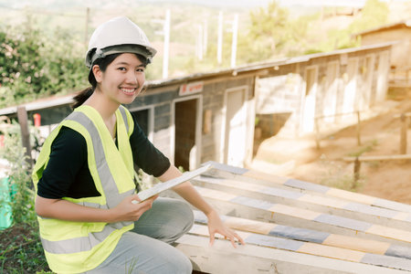 Asian female engineer Wearing a green safety shirt Sitting in the construction area.