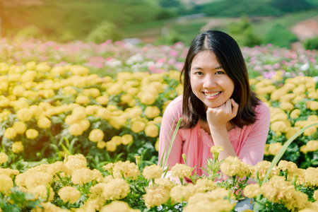 Asian beautiful woman Wearing a pink shirt Standing happily smiling in a yellow flower garden Behind...
