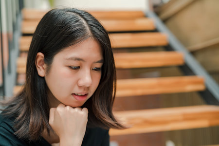 Closeup Asian beautiful woman Wearing a black shirt Sitting in the stairs in the house Use a laptop...