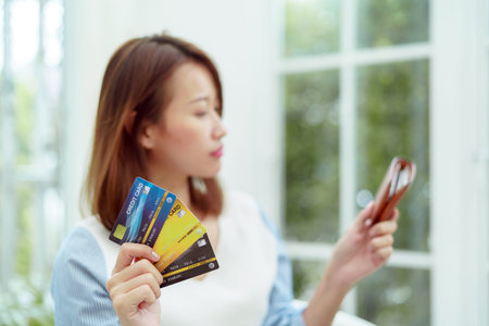 Several credit cards are in the hand of a beautiful Asian woman with the woman out of focus. Happy...