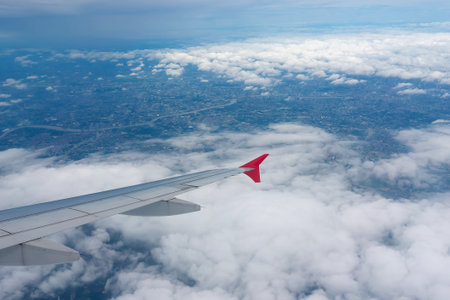A shot through a window of an airplane shows the wings and the view below, with a number of clouds...