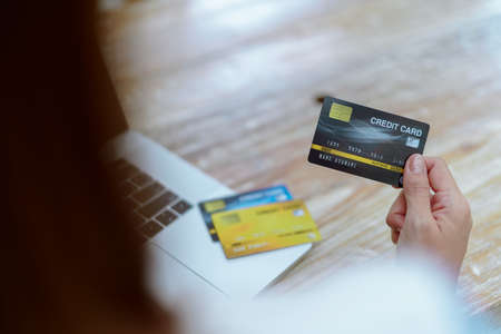 Close Up Credit card in the hand of a young woman near the computer.の写真素材