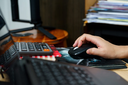 Close Up A woman's hand is holding on a black mouse to operate the computer.