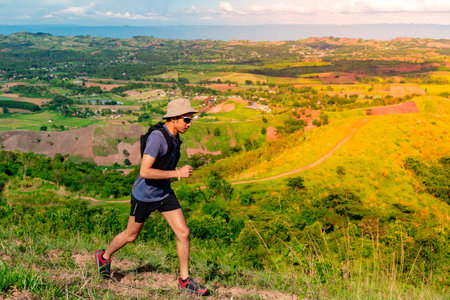 Asian male trail runners wearing sportswear Practicing running on a high mountain behind a beautiful...