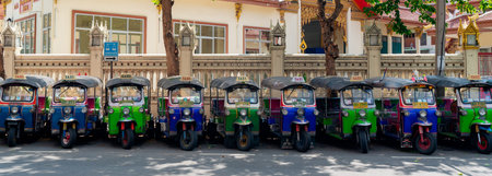 BANGKOK, THAILAND - 20 April 2020 :Many of Bangkok's unique tuk-tuk taxis are parked beside the...