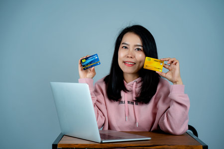 Portrait of an Asian girl wearing a pink shirt. in mobile credit card sitting on a laptop computer...
