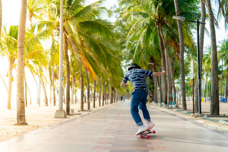 A young Asian man in a striped shirt and trousers is figure skating on a beach filled with coconut palms, during a clear sky time. and no people beach , surf skating, Bangsaen, Thailandの写真素材