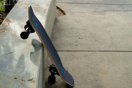 A black server skate has a black top and black wheels resting on a cement floor in a garden.の写真素材