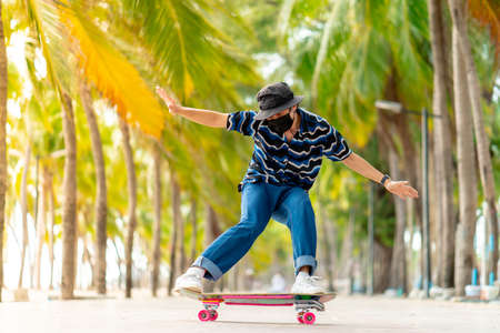 A young Asian man in a striped shirt and trousers is figure skating on a beach filled with coconut palms, during a clear sky time. and no people beach , surf skating, Bangsaen, Thailandの写真素材