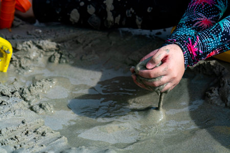 Picture of an Asian girl's hand in a swimsuit. Sitting in a pile of sand by the sea There was wet...