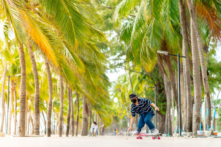 A young Asian man in a striped shirt and trousers is figure skating on a beach filled with coconut...