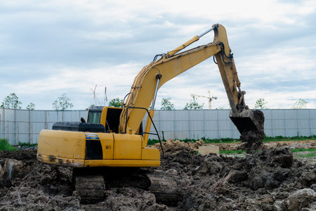 big yellow backhoe Digging the soil to make a drainage channel at the construction site