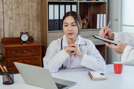 Asian female medical student wearing a white shirt  ask for advice. about the sickness of the patient and the doctor's teacher in the office of the hospitalの写真素材