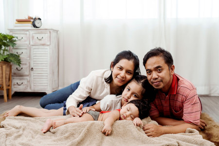 An Asian family of 4 happily playing on the bed in the bedroom with a newborn baby in bed. Concept...