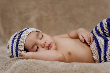 3-month-old Asian newborn in a knitted sweater is happily sleeping warmly on the rug in the bedroom....