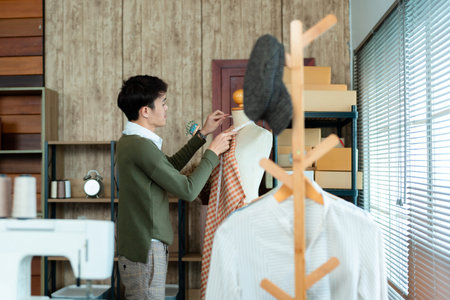 oung Man Asian LGBTQ , The shop assistant is designing the dress, is pinning the cloth in the...