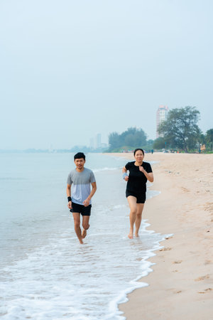Young Asians jogging by the sea in the morning, where the air is fresh and the sky is bright, the...